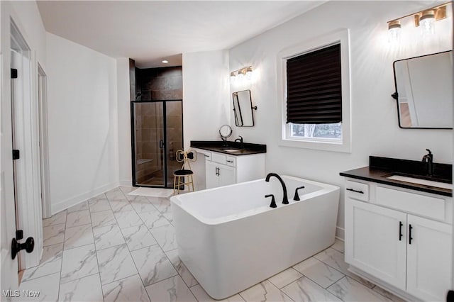 bathroom with marble finish floor, a freestanding tub, a stall shower, and a sink