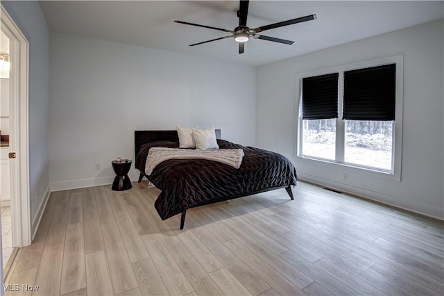 bedroom featuring a ceiling fan, light wood-style flooring, visible vents, and baseboards