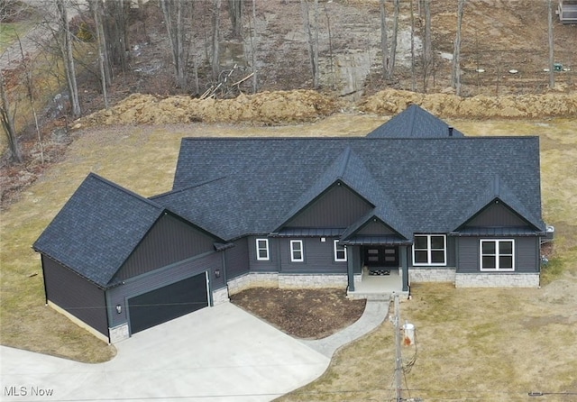 view of front facade featuring a shingled roof, a front yard, driveway, and an attached garage