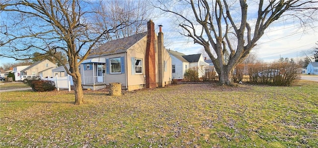 view of side of home with a residential view, a lawn, and a chimney