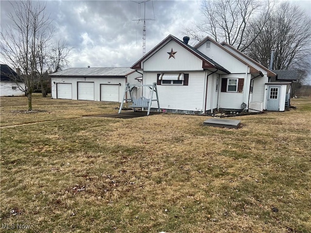 view of front facade featuring a garage, a front yard, and an outbuilding