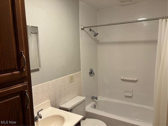 bathroom featuring toilet, shower / tub combo, vanity, and tile walls