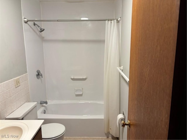 bathroom with toilet, vanity, tile walls, and shower / bathtub combination with curtain