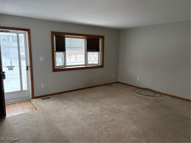 carpeted spare room featuring a wealth of natural light and baseboards