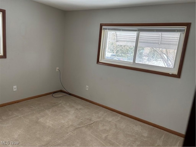 unfurnished room featuring baseboards and light colored carpet