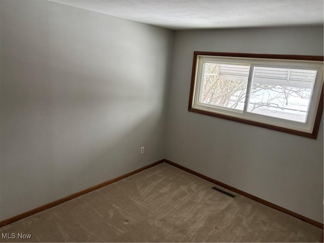 spare room featuring carpet flooring, visible vents, and baseboards