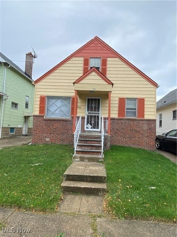 view of front of property with brick siding, crawl space, and a front yard