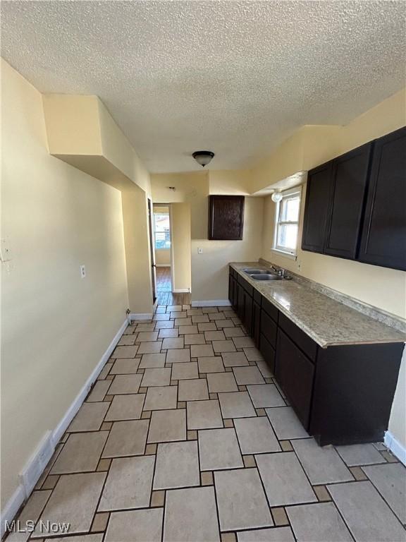 kitchen featuring baseboards, light countertops, and dark cabinetry