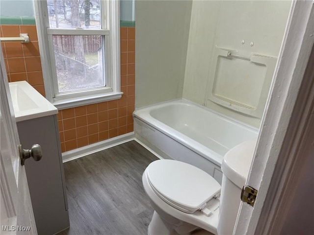 full bath featuring toilet, shower / bath combination, tile walls, and wood finished floors