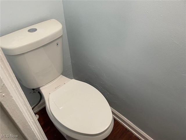 bathroom with wood finished floors, toilet, and baseboards