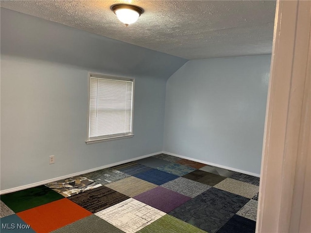 bonus room featuring a textured ceiling, lofted ceiling, and baseboards