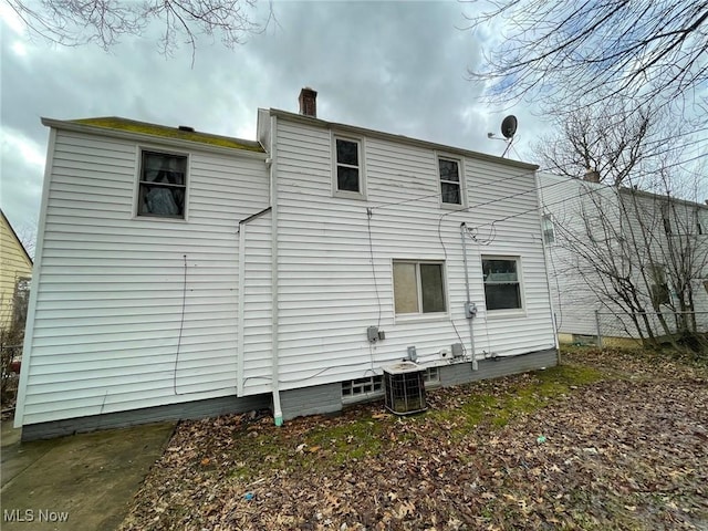 rear view of house featuring a chimney and cooling unit