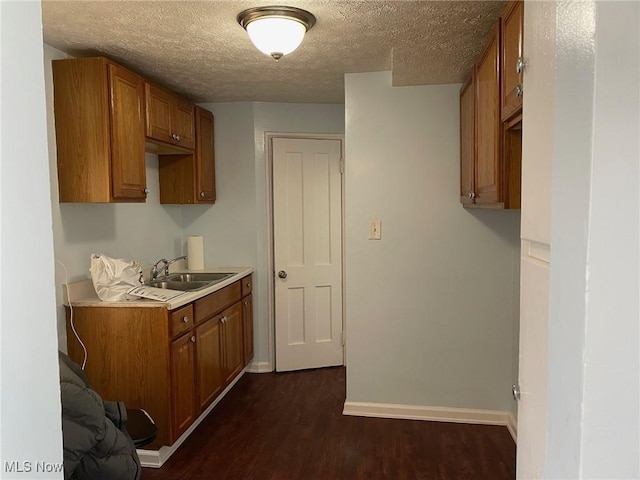 kitchen with dark wood-type flooring, light countertops, a sink, and brown cabinetry