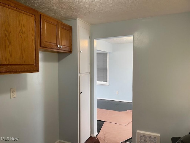 interior space featuring a textured ceiling, dark wood-style floors, and baseboards