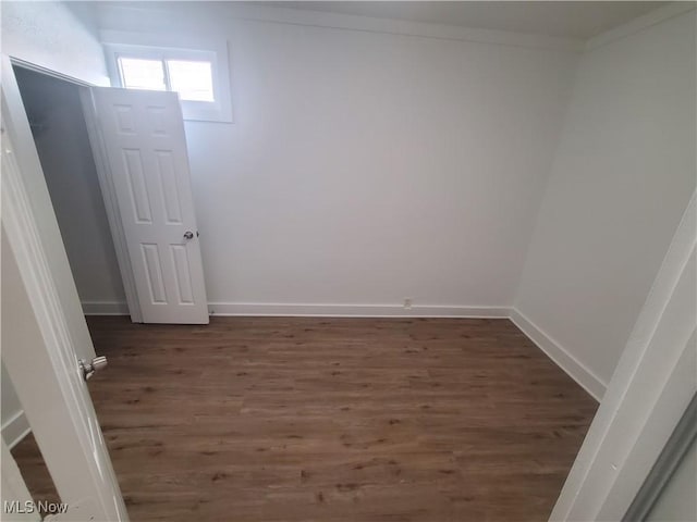 spare room with crown molding, baseboards, and wood finished floors