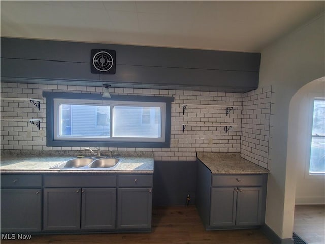 bathroom with baseboards, wood finished floors, a sink, and decorative backsplash