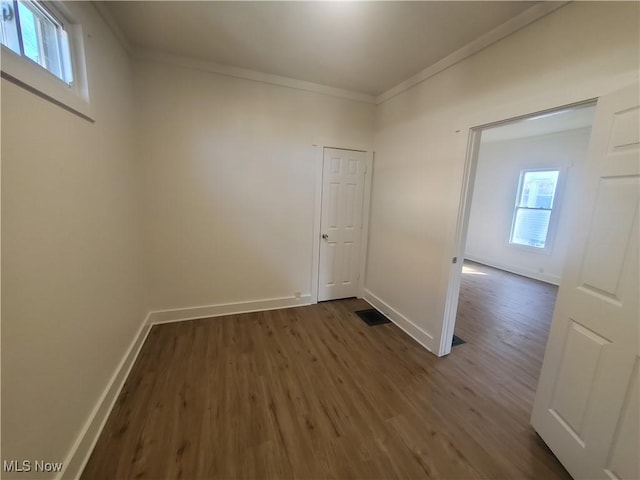 unfurnished room with ornamental molding, plenty of natural light, baseboards, and dark wood-style floors