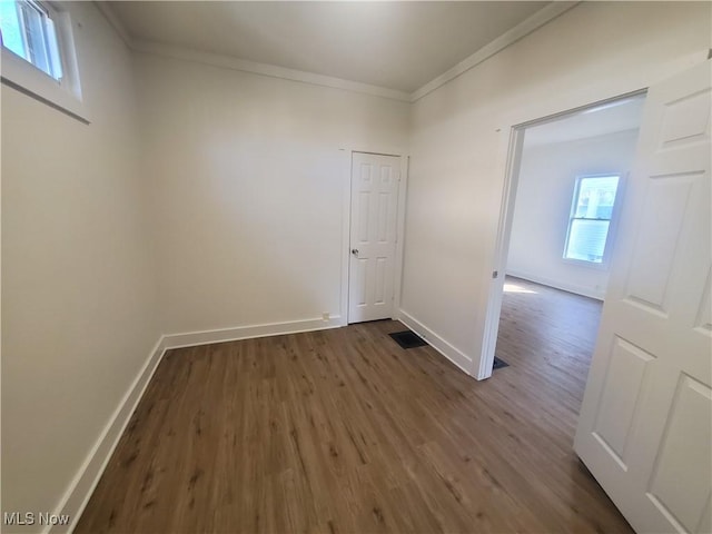 unfurnished room featuring baseboards, visible vents, ornamental molding, and dark wood-type flooring