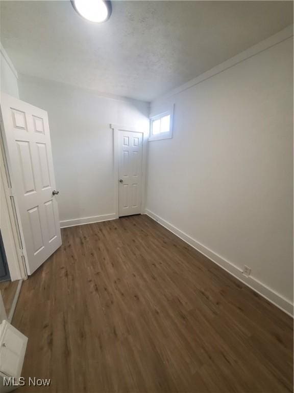 empty room featuring dark wood-style flooring and baseboards