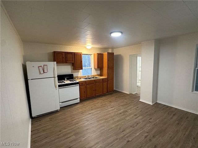 kitchen with white appliances, dark wood-type flooring, a sink, baseboards, and brown cabinets