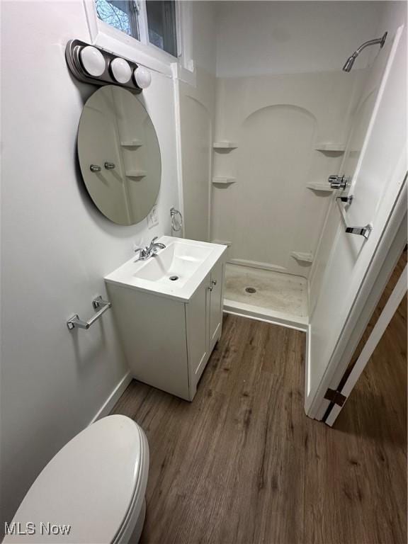 bathroom featuring toilet, a stall shower, wood finished floors, and vanity