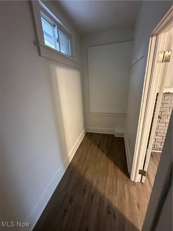 hallway featuring baseboards and dark wood-type flooring