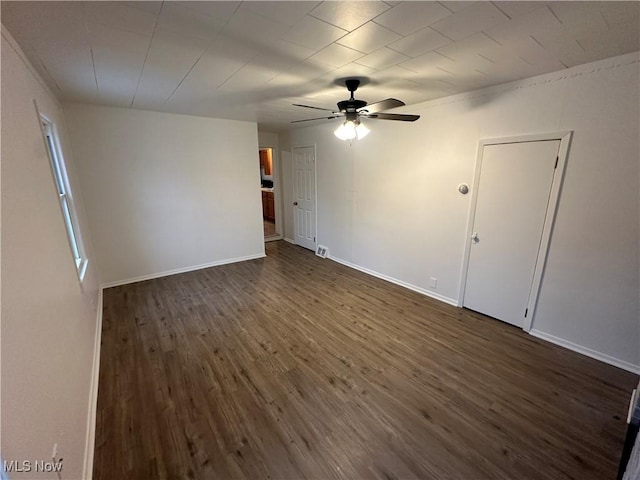 empty room with ceiling fan, baseboards, and dark wood finished floors