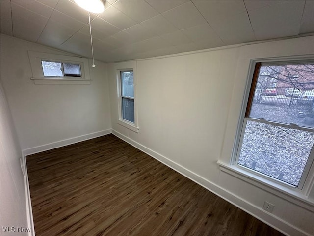 empty room featuring vaulted ceiling, baseboards, and dark wood finished floors