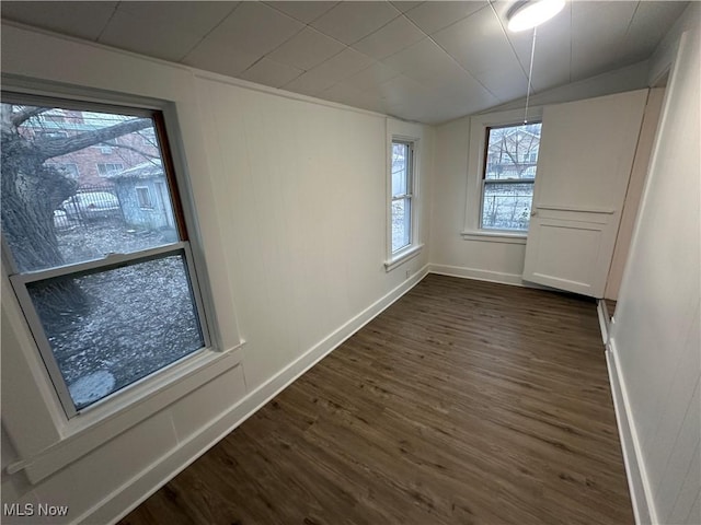 empty room featuring dark wood-style floors, vaulted ceiling, and baseboards