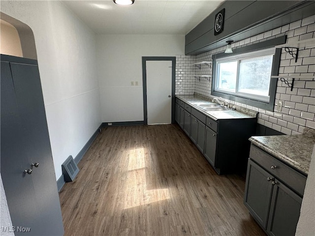 kitchen featuring tasteful backsplash, wood finished floors, visible vents, and baseboards