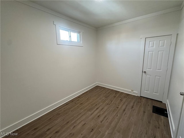 spare room with baseboards, dark wood finished floors, and crown molding