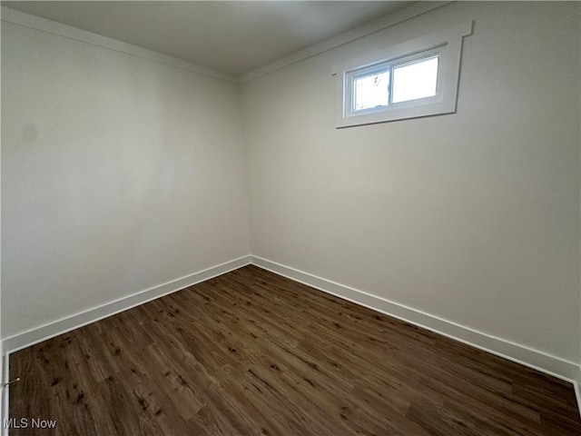 spare room featuring baseboards, dark wood-style flooring, and ornamental molding