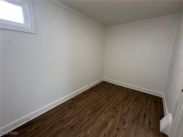 unfurnished room with dark wood-style floors, baseboards, and crown molding