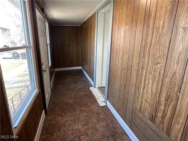 corridor featuring wood walls and baseboards