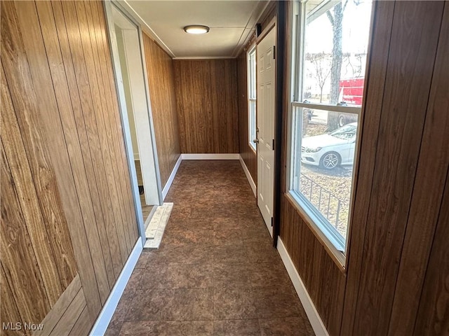 hall featuring a wealth of natural light, wood walls, and a barn door