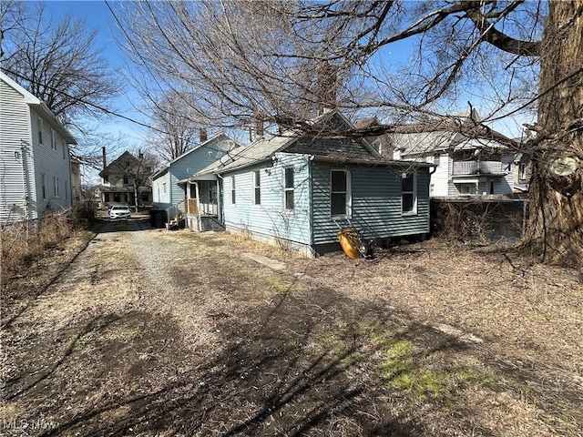 view of side of property with fence and dirt driveway