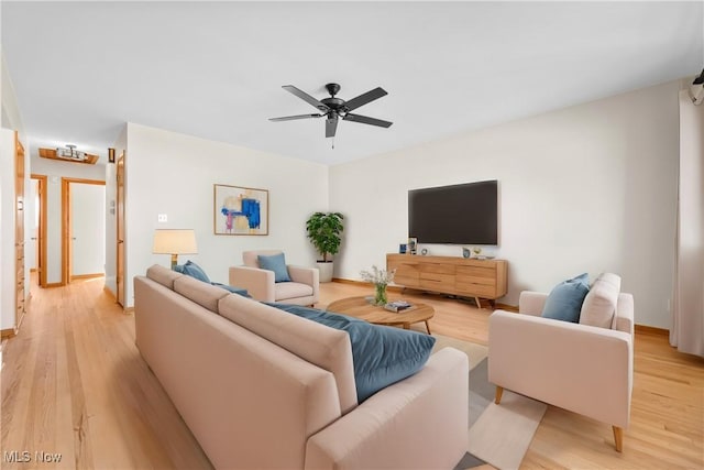 living area featuring light wood finished floors, baseboards, and a ceiling fan