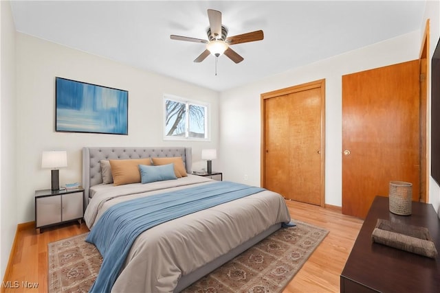 bedroom featuring ceiling fan, baseboards, two closets, and light wood-style flooring