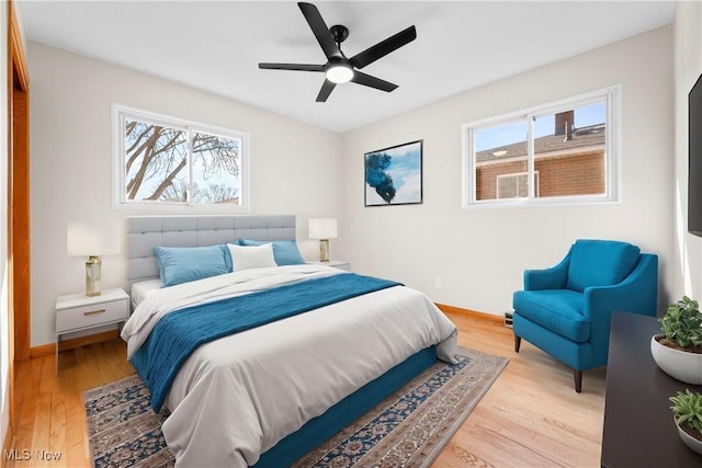 bedroom featuring baseboards, multiple windows, and light wood finished floors