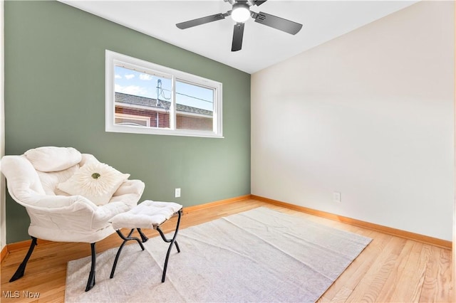 living area featuring lofted ceiling, baseboards, and wood finished floors