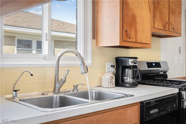 kitchen with gas range, light countertops, black dishwasher, brown cabinets, and a sink