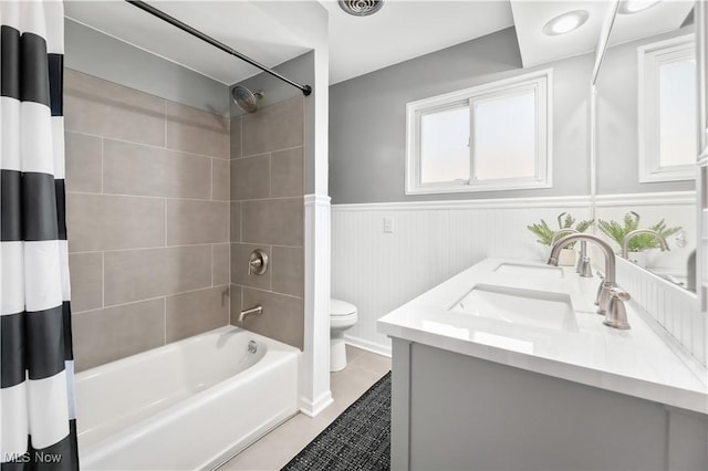 full bathroom featuring shower / bathtub combination with curtain, toilet, a sink, wainscoting, and double vanity