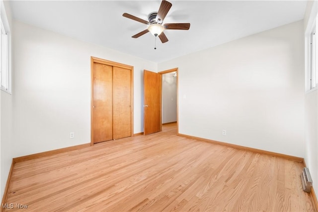 unfurnished bedroom featuring a closet, a ceiling fan, light wood-type flooring, and baseboards