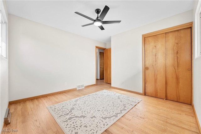 bedroom featuring light wood finished floors, visible vents, a closet, and baseboards