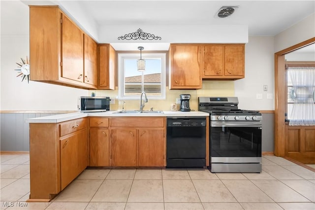 kitchen with visible vents, a sink, stainless steel appliances, brown cabinetry, and light countertops