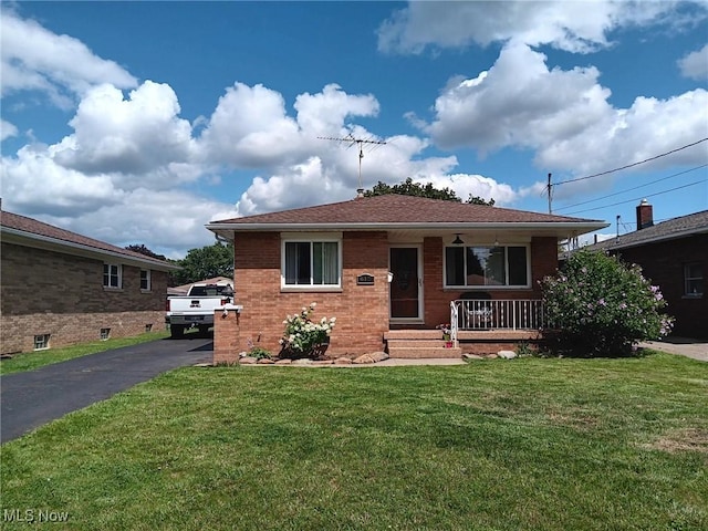 view of front of property featuring brick siding, covered porch, driveway, and a front lawn