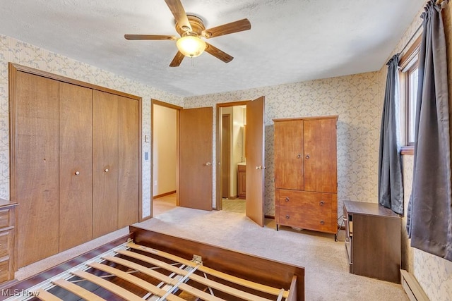 bedroom with carpet floors, a closet, baseboard heating, and wallpapered walls