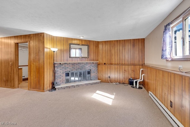 unfurnished living room with carpet floors, a brick fireplace, wood walls, and baseboard heating