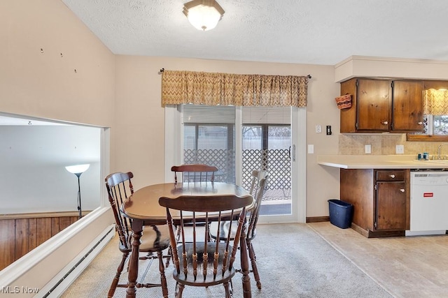 dining area featuring light carpet, baseboard heating, a textured ceiling, and baseboards