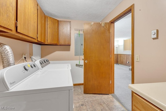 laundry area with a wainscoted wall, cabinet space, washing machine and dryer, wooden walls, and a textured ceiling